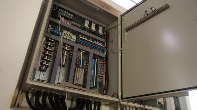 Open cabinet with modern switch gear breakers and wires to control electrical equipment in light room extreme close view