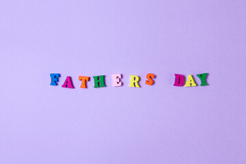 Child's toy letters spelling Fathers Day on purple background
