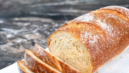 Closeup of a partially sliced loaf of homemade artisan wheat bread, with crunchy crust and open crumb. Selective limited depth of field focus. Noise grainy from bread texture.