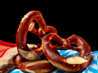 Three freshly baked pretzels and arranged on a black background.Traditional Bavarian food
