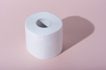 Roll of toilet paper with shadow on a pink background.
