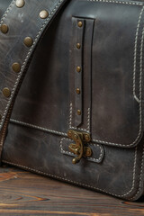Close-up of the belt buckle of a retro style dark leather messenger bag.