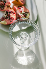 The background is white with shadows from a crystal glass, pomegranate.