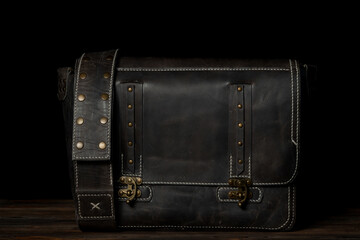 Retro style dark leather messenger bag with rivet straps.