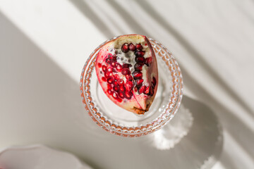 The background is white with shadows from a crystal glass, pomegranate.