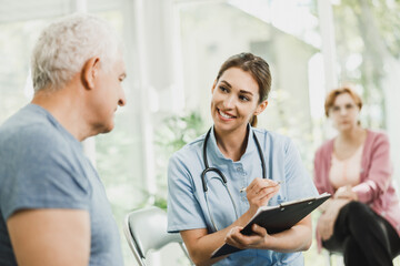 Nurse Talking To Senior Man At Waiting Room