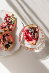 The background is white with shadows from a crystal glass, pomegranate.