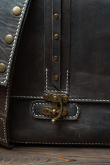 Close-up of the belt buckle of a retro style dark leather messenger bag.