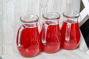 three decanters with red berry juice on the sideboard.