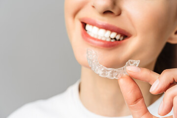 A young woman does a home teeth whitening procedure. Whitening tray with gel