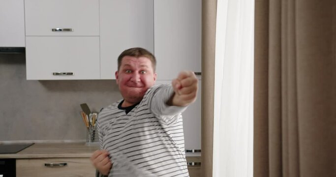 Excited man celebrating success in kitchen