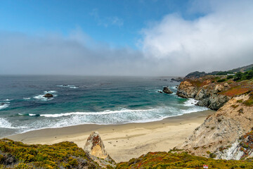 Beach Pacific Ocean Rocks with fog clouds misting and blue sky