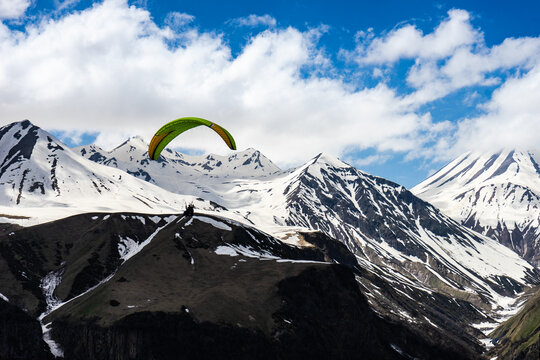 Paraglider flying over Caucasus mountains, Gudauri, Georgia