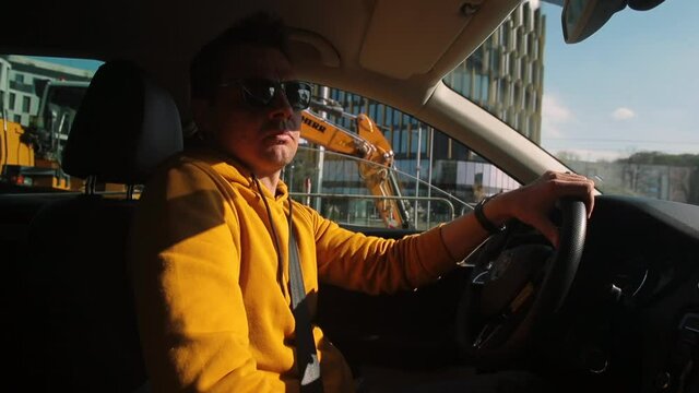 A male taxi driver gets out of the car at a bus stop. End of movement, pause in car control. Yellow clothes.