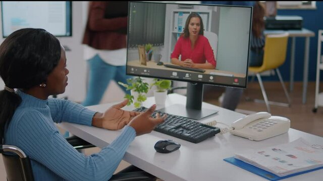 Black paralized invalid handicapped employee discussing with remote manager using video call talking online company problems during virtual meeting sitting in wheelchair. strat up business office.
