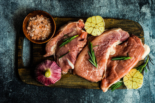 Overhead view of raw pork steaks with garlic, rosemary and pink Himalayan salt