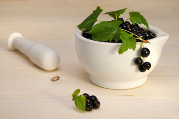 black currant in a mortar and a pestle for making jam