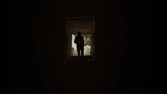 Young man with a flashlight enters the tunnel. Fear and horror