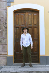 Handsome young man wearing hat. Street portrait of young man standing next to a gate.