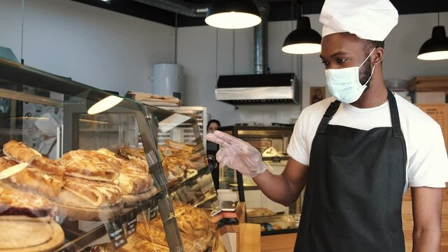 Fine African American man in mask offering pastry