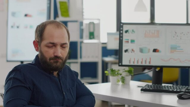 Close up of disabled invalid entrepreneur sitting in wheelchair looking at camera sad working in economic business company at computer prosessing financial information, graphs monitoring economy