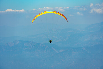 Paraglider soaring on paragliding in the sky in mountain. Extreme sport in mountains