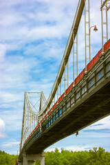 A modern pedestrian cable-stayed bridge against a blue cloudy sky in summer day.