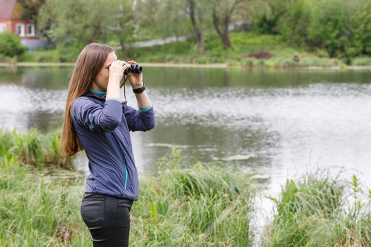 Woman birdwatcher looking for the bird on the lake