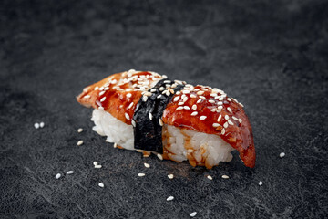 Sushi with smoked eel and sesame seeds on a stone background. Japanese dish Unagi sushi, close up