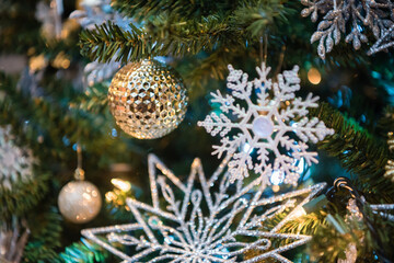 Obraz na płótnie Canvas Christmas tree ornaments with gold bulbs and glitter snowflakes. Close up