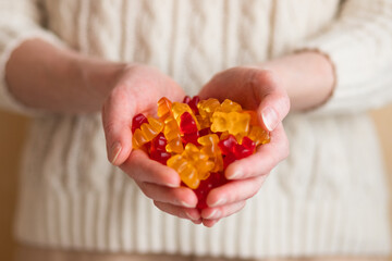 Close-up image of a woman holding multi-colored gummy bears.