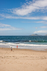 Bucolic image of people observing the Cíes Islands from a beach in the Ría de Vigo