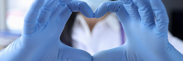 Hand of doctor in protective medical gloves is covering heart closeup