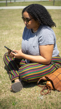 Young woman sitting in a park and sending a text