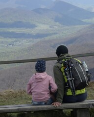 Spring trip to the Bieszczady mountains with a kid. Father and doughter sitting on the bench,...