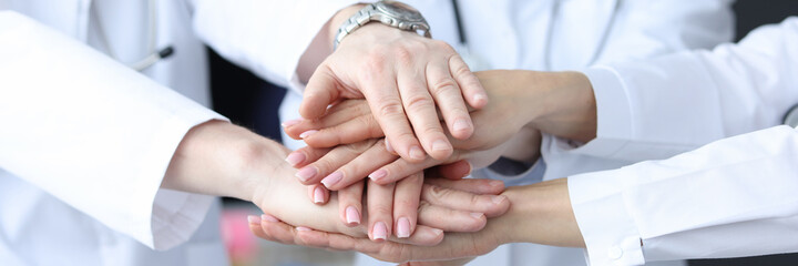 Group of doctors putting their hands together in clinic closeup