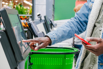 The finger of an African man in close-up at the supermarket checkout selects the desired product on...