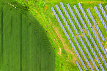 Aerial view of solar power plant on green field. Electric panels for producing clean ecologic energy.