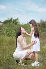 Mom hugs and kisses her daughter outdoors. Happy family concept. 