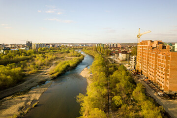 Obraz premium Aerial view of tall residential apartment buildings under construction and Bystrytsia river in Ivano-Frankivsk city, Ukraine.
