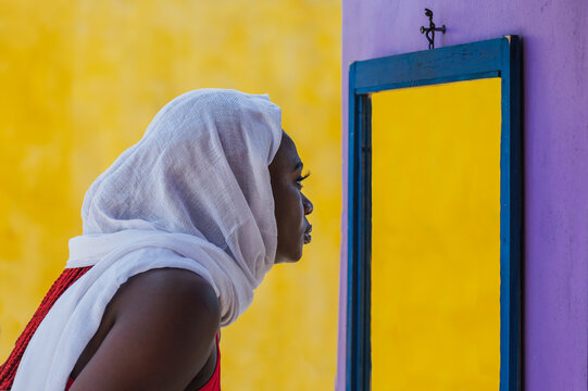 Africa The woman looks in an empty mirror with a white shawl covering her hair