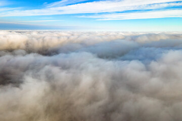 Aerial view from above of white puffy clouds in bright sunny day.