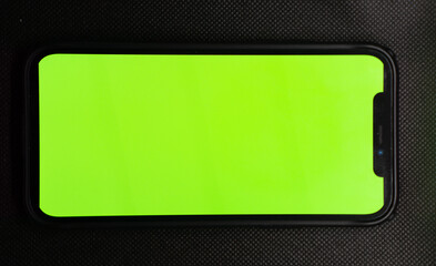 Man's hand shows mobile smartphone with green screen in vertical position isolated