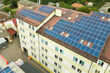 Aerial view of solar power plant with blue photovoltaic panels mounted of apartment building roof.