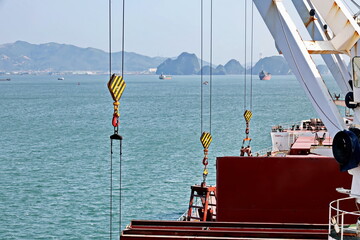 Loading bulk cargo of limestone from barges into a bulk carrier by using ship cranes and grabs at...