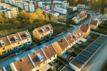 Fototapeta premium Aerial view of residential houses with red roofs and streets with parked cars in rural town area. Quiet suburbs of a modern european city.