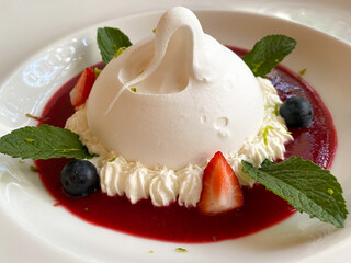 Delicious Pavlova dessert on a white plate close-up. Pavlova dessert is an airy soft cloud and an amazing taste combination of berries, butter cream and protein dough