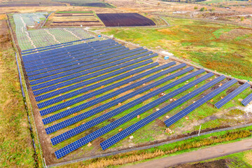 Fototapeta na wymiar Aerial view of solar power plant under construction on green field. Assembling of electric panels for clean ecologic energy production.