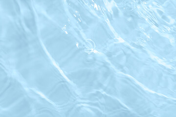 Surface of light blue transparent swimming pool water. Texture of transparent blue water in swimming pool. Trendy abstract nature background. Water waves in sunlight with copy space