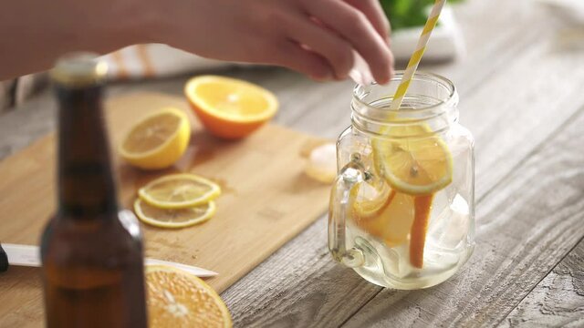 Preparing a summer refreshing drink with lemon and orange wedges. A glass with a handle on the table is filled with slices of lemon and orange. Preparation of healthy refreshing drinks on the table
